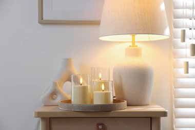 Decorative LED candles, vases and lamp on wooden table indoors