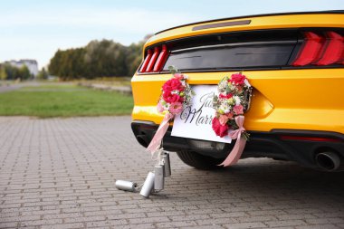 Düğün arabası. Cabriolet, Yeni Evli kartıyla dekore edilmiş, güzel çiçekler ve teneke kutular, yakın plan. Metin için boşluk