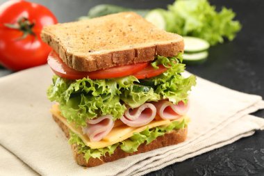 Tasty sandwich with ham, cheese and vegetables on grey table, closeup