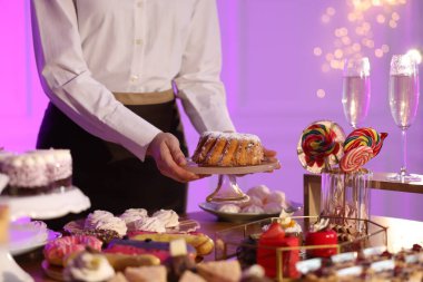 Garson açık büfe masasında lezzetli tatlılar hazırlıyor, yakın plan.