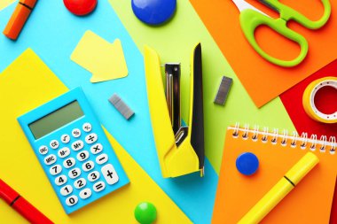 Stapler and other stationery on red background, flat lay