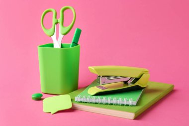 Stapler and other stationery on pink background. Space for text