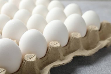 Yumurta kutusunda çiğ tavuk yumurtası. Gri masada, yakın plan.