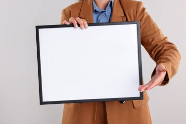 Açık arkaplanda boş diploma çerçevesi olan bir kadın, yakın plan. Tasarım için model