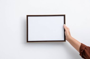 Beyaz duvara boş bir diploma çerçevesi asan kadın, yakın plan. Tasarım için model