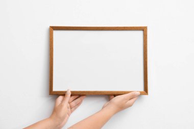 Beyaz duvara boş bir diploma çerçevesi asan kadın, yakın plan. Tasarım için model