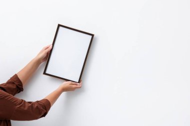 Beyaz duvara boş bir diploma çerçevesi asan kadın, yakın plan. Tasarım için model