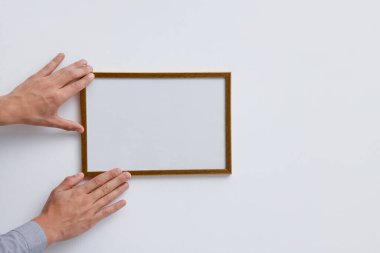 Beyaz duvara boş bir diploma çerçevesi asan adam, yakın plan. Tasarım için model