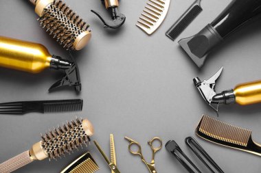 Frame of different hair styling tools on grey background, flat lay. Space for text