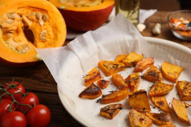 Baked pumpkin and ingredients on wooden table, closeup