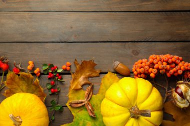 Dry autumn leaves, pumpkins, acorns, chestnut and berries on wooden table, flat lay. Space for text