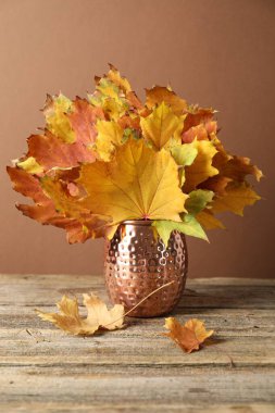 Sonbahar atmosferi. Kahverengi arka planda, ahşap masada kuru yapraklı vazo.