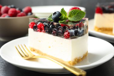 Lezzetli peynirli kek, böğürtlenli ve nane şekerli, siyah ahşap masa, yakın plan.