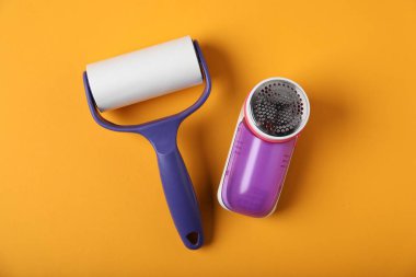 Lint roller and fabric shaver on orange background, flat lay