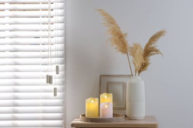 Decorative LED candles and other decor on wooden bedside table indoors