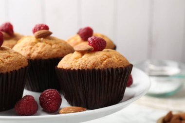 Fresh muffins with raspberries and almonds on table, closeup