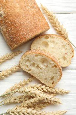 Beyaz ahşap masada gevrek ciabatta ve buğday kulakları.
