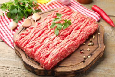 Maydanozlu çiğ et ve ahşap masada baharatlar, yakın plan.