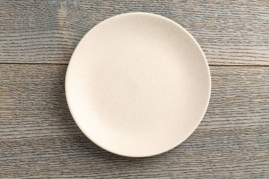 Clean ceramic plate on wooden table, top view