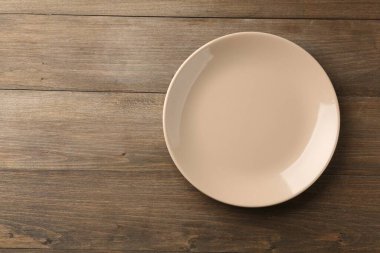Stylish ceramic plate on wooden table, top view. Space for text