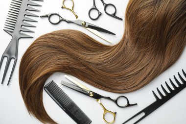 Güzel kahverengi saç ve kuaför aletleri beyaz arka planda, düz yatıyordu.