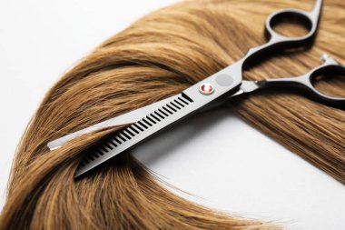 Beyaz arka planda güzel saç teli ve makas, yakın plan.