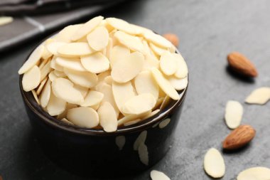 Taze badem gevrekleri kasede ve fındıklar gri masada, yakın plan.