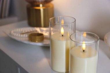 Beyaz dolaptaki dekoratif LED mumlar ve mücevherler, yakın plan.