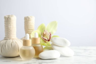Beyaz mermer sehpanın üzerinde arkaplanda gerekli yağlar ve bitkisel torbalar bulunan güzel bir spa kompozisyonu. Metin için boşluk