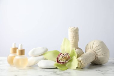 Beyaz mermer sehpanın üzerinde hafif arka planda gerekli yağlar ve bitkisel poşetlerle güzel bir spa kompozisyonu.