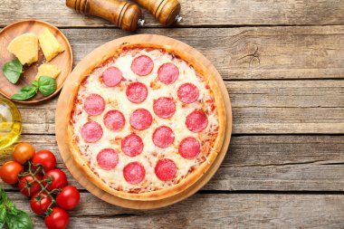 Delicious pepperoni pizza and ingredients on wooden table, flat lay. Space for text