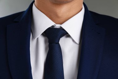 Gri arka planda şık kravatlı takım elbiseli adam, yakın plan.