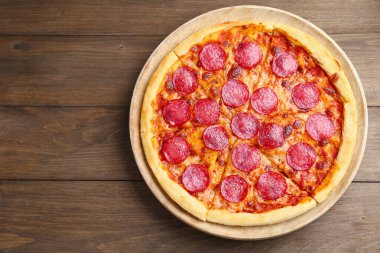 Ahşap masada nefis kesilmiş pepperoni pizza, üst manzara. Metin için boşluk