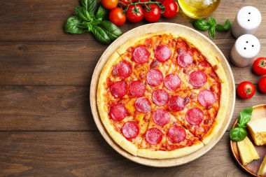 Delicious pepperoni pizza and ingredients on wooden table, flat lay. Space for text