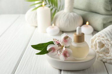 Beautiful spa composition with essential oil and burning candles on white wooden table, closeup. Space for text