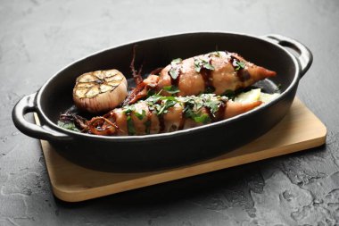 Siyah masada soslu ve sarımsaklı lezzetli kalamarlar, yakın plan.