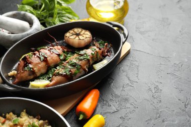 Soslu, sarımsaklı ve siyah masadaki ürünlerle pişirilmiş lezzetli kalamarlar, yakın plan. Metin için boşluk