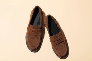 Bej arka planda bir çift şık kahverengi ayakkabı.