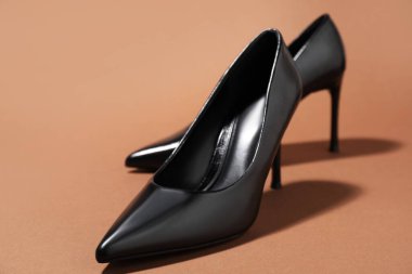 Kahverengi arka planda şık topuklu ayakkabılar, yakın plan.