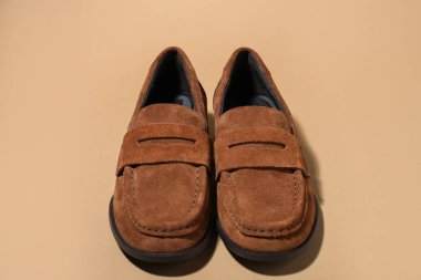Pair of stylish brown shoes on beige background, closeup