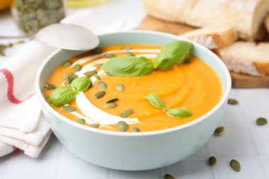 Beyaz fayanslı masada servis edilen lezzetli balkabağı çorbası, yakın plan.