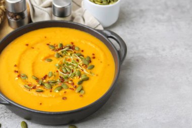 Delicious pumpkin soup served on grey table, closeup. Space for text