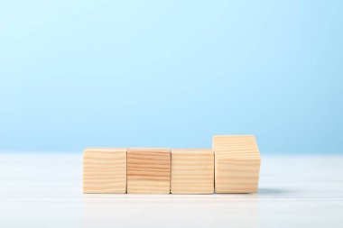 Açık mavi arkaplana karşı beyaz ahşap masa üzerindeki boş küpler, metin için boşluk