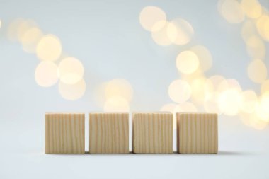 Blank wooden cubes on light background with blurred lights, space for text. Bokeh effect