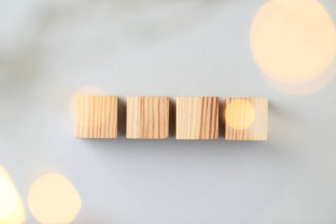 Blank wooden cubes on light grey background, flat lay. Bokeh effect