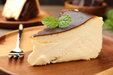 Pieces of delicious Basque cheesecake with mint on table, closeup
