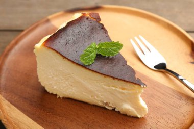 Bir parça lezzetli Bask peynirli keki. Masada çatal ve nane var. Yakın plan.