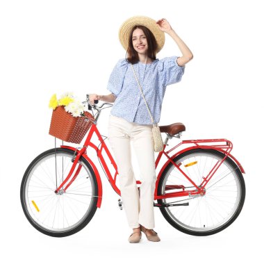 Beyaz arka planda çiçek sepeti olan şapkalı ve bisikletli gülümseyen kadın.