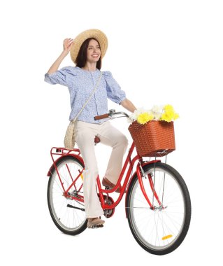 Şapkalı gülümseyen kadın beyaz arka planda bir sepet çiçekle bisiklet sürüyor.