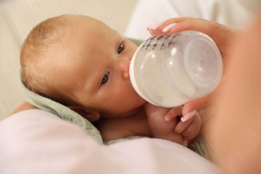 Anne yeni doğmuş bebeğini biberonla besliyor.